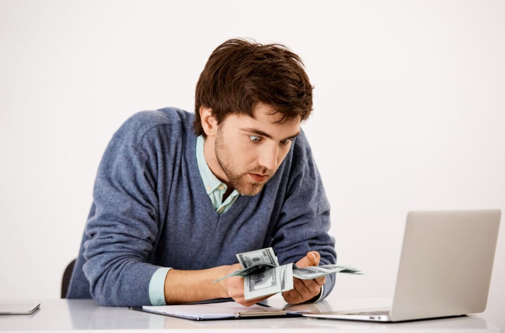 Surprised man counting damaged money at desk
