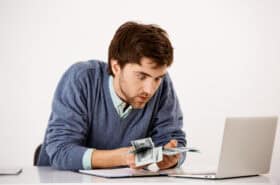 Surprised man counting damaged money at desk
